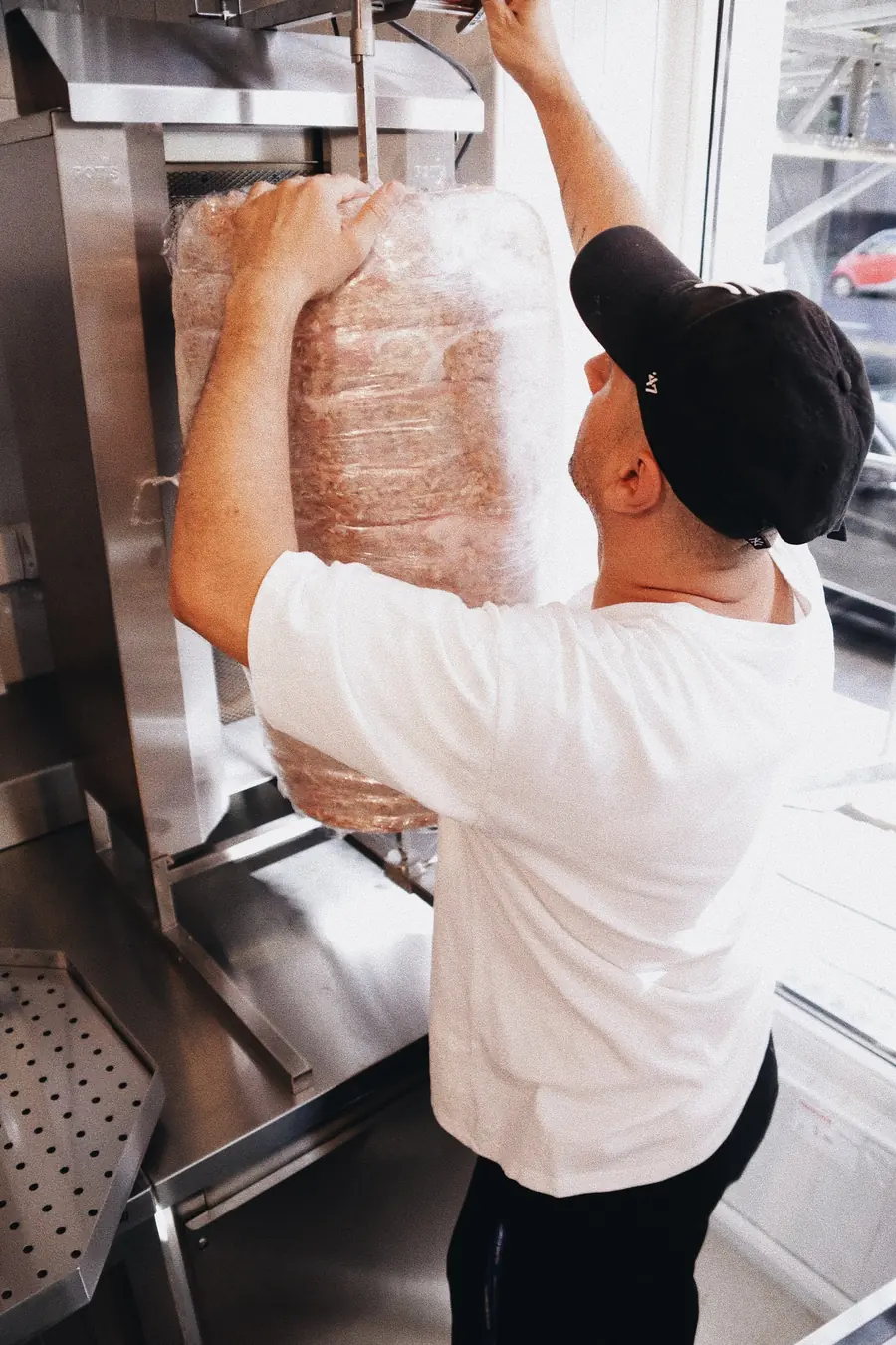 Der geschichtete Spieß wird am Grill aufgehängt